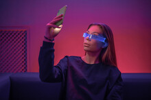Young Woman In Glowing Glasses Uses The Phone