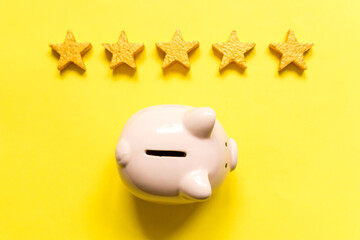 Simply minimal design piggy bank 5 gold stars isolated on yellow background. Bank rating. Saving investment budget business retirement financial money banking concept. Flat lay top view copy space.