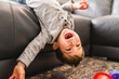 © Louis-Paul Photo - Little boy is standing on sofa at home upside down