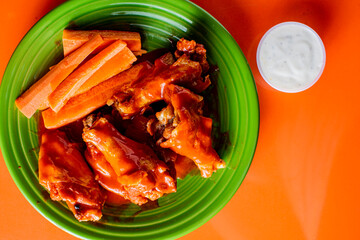 Chicken wings. Chicken wings served spicy buffalo wing sauce and honey barbecue sauce. Served with ranch dressing, blue cheese, celery and carrots. Classic American style bar or pub favorite fare.