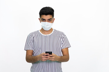 Young man wearing a white striped shirt. He's wearing a medical mask. He has a cell phone. White background. Isolated image.