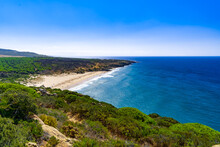 Playa Rodeada De Vegetación Con Agua Del Mar Y Cielo Azul Un Día Soleado En Un Entorno Natural Salvaje. Desde Zahara De Los Atunes, Cádiz, Andalucía, España.