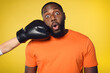 © alphaspirit - Shocked black man receives a punch from somebodies. yellow background