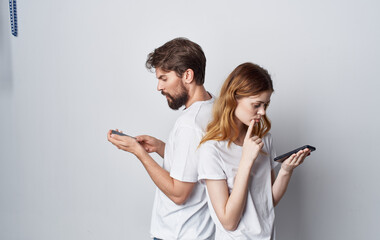 man and woman in white t-shirts with phones in hands romance communication technology