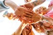 © Impact Photography - Friends gathered in circle holding hands together in the middle