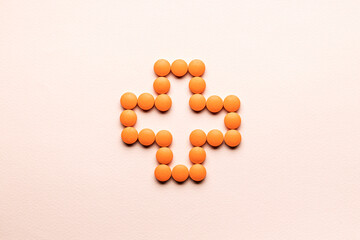 Wall Mural - pill cross shape isolated over pastel pink background. creative minimal. studio shot. above view. pharmacy concept