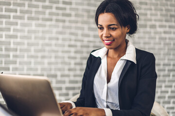 Portrait of smiling happy african american black woman relaxing using technology of laptop computer while sitting on table.Young creative african girl working at home.work from home concept