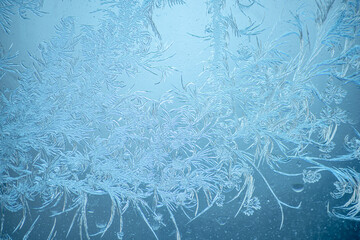 Beautiful sparkling natural frost pattern on the blue window glass