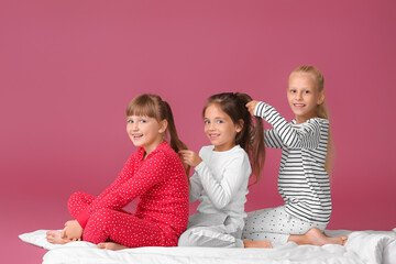 cute little girls making braids on color background