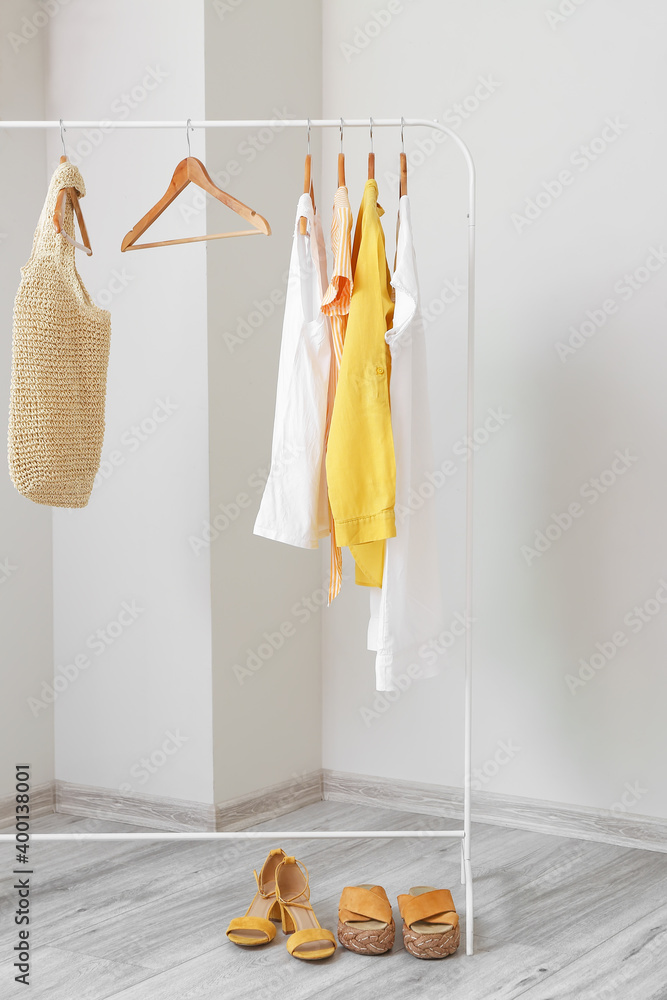 Rack with clothes and accessories in room