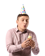 Poster - Young man blowing out candle on birthday cupcake against white background