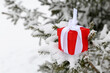 Red gift box with white bow on the snow covered fir branch. Romantic present for Christmas or New Year holiday