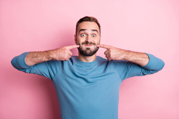 Wall Mural - Photo of cute funny young man dressed blue sweater fooling pointing cheeks isolated pink color background