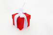 Red gift box with white bow on the snow. Romantic present for Christmas or New Year holiday