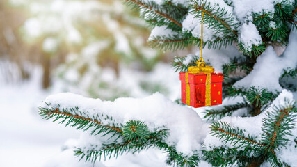 Christmas decoration in the form of a gift on a spruce branch covered with natural snow. Winter christmas picture