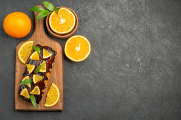 Above view of tasty cakes whole and cut lemons on cutting board on black table