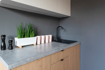 Wall Mural - Marble counter in the modern kitchen with sink, faucet, mugs, plant and wooden cabinet and furniture. Minimalism and scandinavian style in modern interior. Copy space.