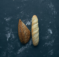 Fresh tasty bread and baguette on a dark textured background.