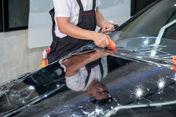 Car wrapping specialist cutting vinyl transparent film on car hood for protection car paint. Protective film. Transparent film. Car paint protection