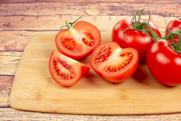 red tomatoes and tomato slices on a wooden board