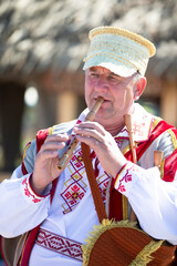 Wall Mural -  An elderly Slavic man in national dress plays the pipe.