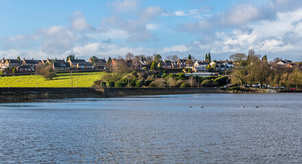 Sticker - A view across Thornton Reservoir towards the village of Thornton, UK on a bright sunny day