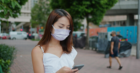 Wall Mural - Woman wear face mask and use of mobile phone at street