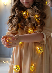 Canvas Print - girl and Christmas glowing garland. A little girl is stay on the floor. Girl holding a garland with glowing stars in her hands