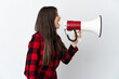 © luismolinero - Teenager Brazilian girl isolated on white background shouting through a megaphone to announce something in lateral position