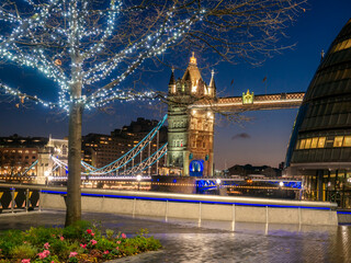 Wall Mural - Tower Bridge of London illuminated at night and a decorated tree in Christmas holiday on the riverside of the Thames