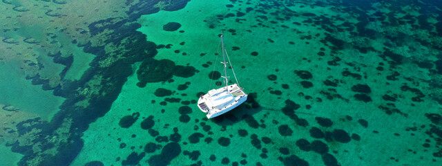 Wall Mural - Aerial drone ultra wide photo of Catamaran sail boat anchored in tropical exotic bay with emerald crystal clear sea