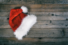 Red Santa Christmas Hat Laid On Rustic Wooden Background.