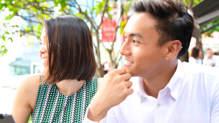 Poster - Young asian couple relaxing outdoor at a restaurant table