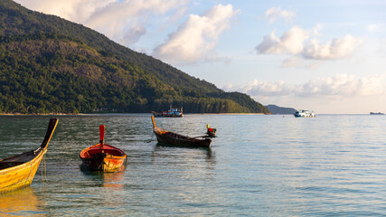 Wall Mural - Selective focus of a peaceful beach during sun rise with golden light and blue sky. Fishing boat background