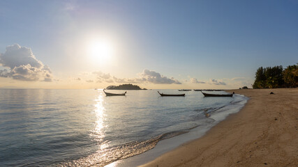 Wall Mural - Selective focus of a peaceful beach during sun rise with golden light and blue sky. Fishing boat background