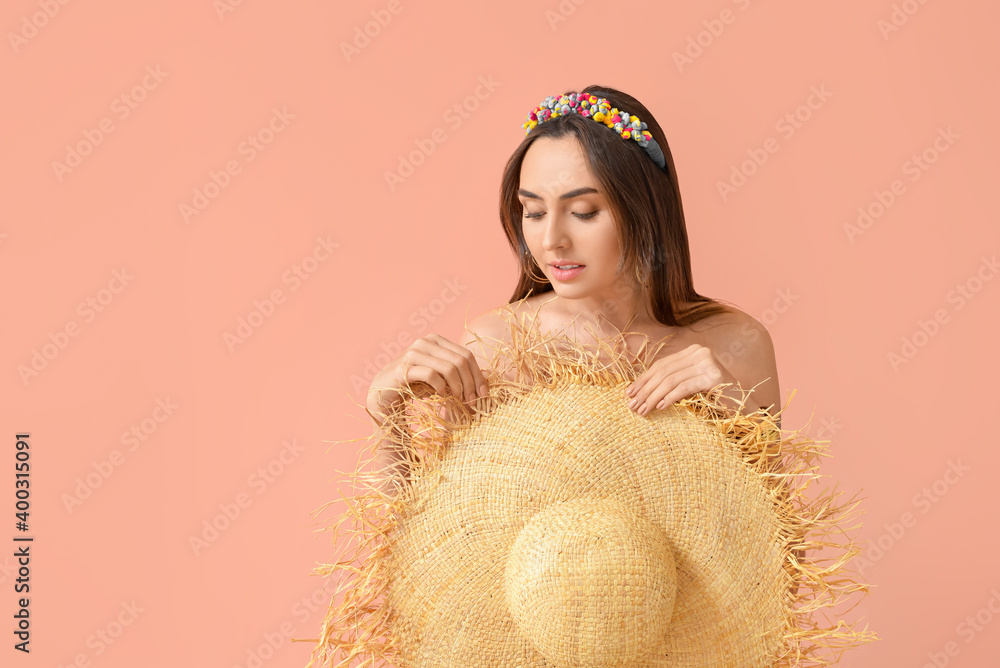 Naked young woman with hat on color background
