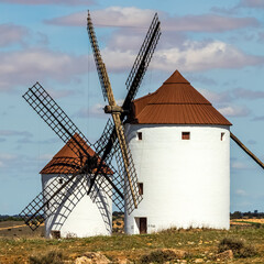 Ancient stone windmills in La Mancha. Blue sky with clouds.
