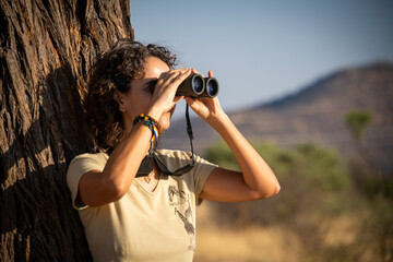 Canvas Print - Close-up of brunette by tree using binoculars