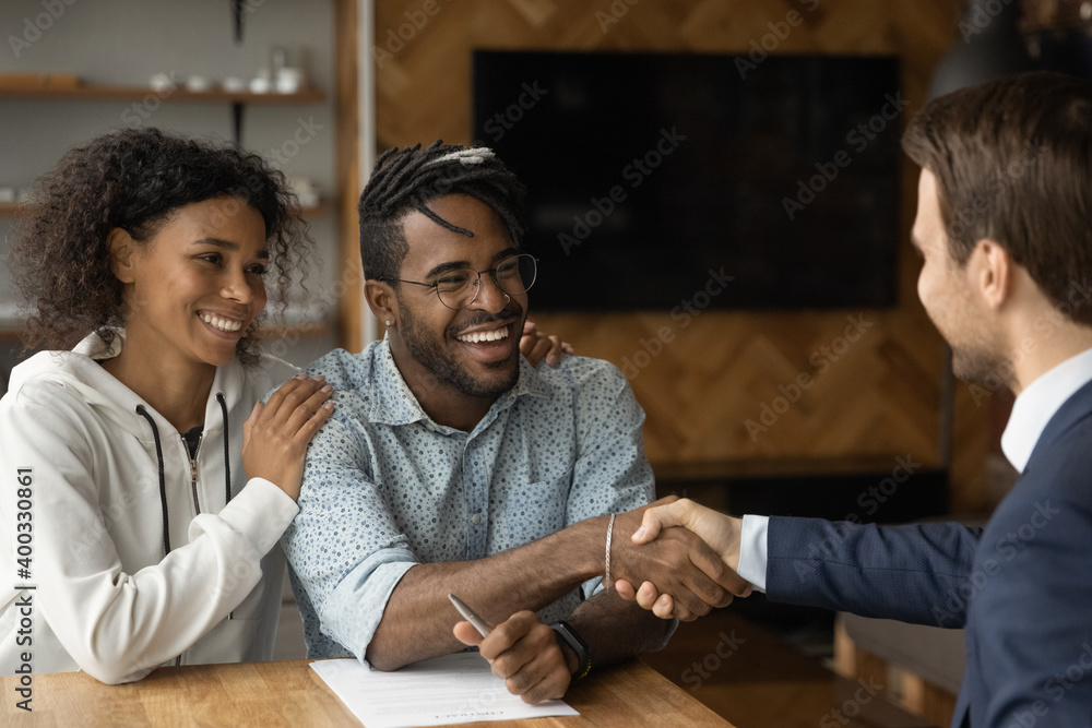 Happy African American couple shake hand close deal with male realtor ...