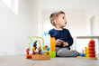 © Miljan Živković - Front view full length of small caucasian boy three years old playing with brick blocks toys on the floor at home or in daycare kindergarten alone with copy space - childhood leisure activity concept