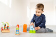 © Miljan Živković - Front view full length of small caucasian boy three years old playing with brick blocks toys on the floor at home or in daycare kindergarten alone with copy space - childhood leisure activity concept