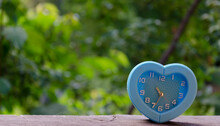 Alarm Clock Leaning On A Wooden Railing With Forest In The Background