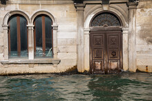 Venice, Italy. Close Up Of A Waterfront Bulding With Wooden Portal Or Door Partlu Submerged By The Water. Water At Very High Level Submerging Steps And Doorways And Almost Touching The Windows.