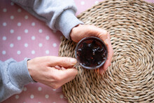 Adult Woman's Hand Holding Red Herbal Tea.on The Pink Polka Dot Tablecloth And Wicker