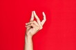 Arm of caucasian white young man over red isolated background snapping fingers for success, easy and click symbol gesture with hand