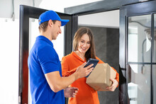 Caucasian Currier Delivery Man In Uniform With Packages For Woman Recipient At The Door. 