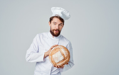 A Chef In a Light Suit and Headdress with a Round Loaf of Bread in His Hand