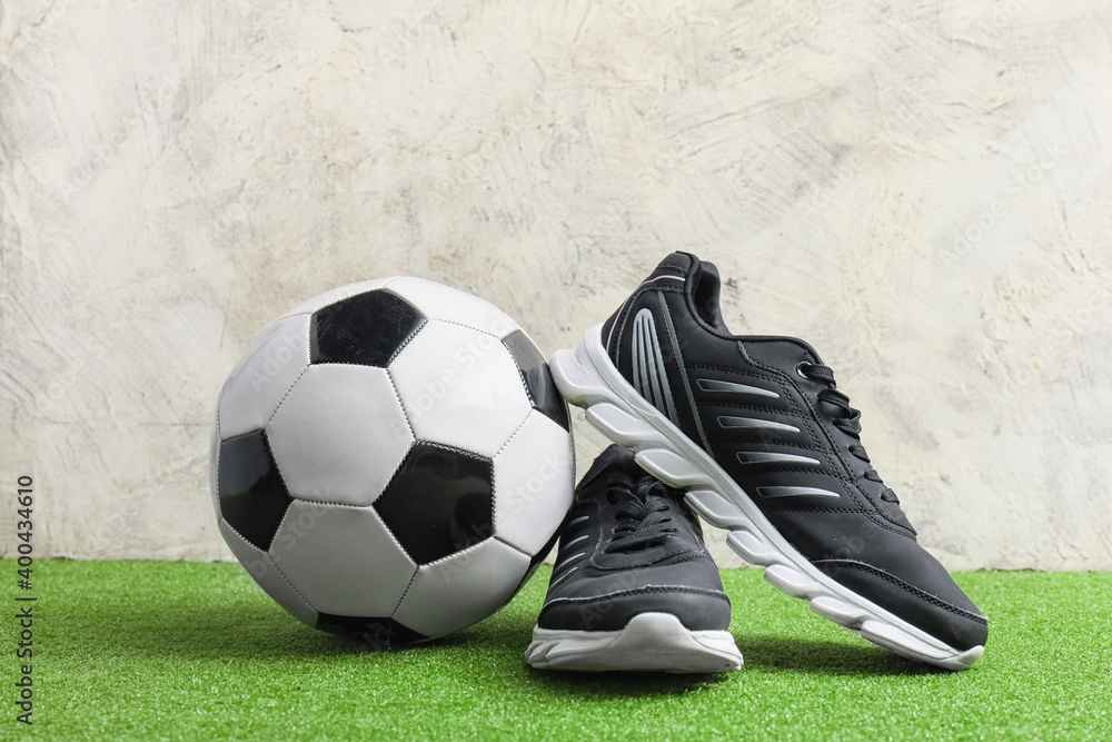 Sneakers and soccer ball near light wall
