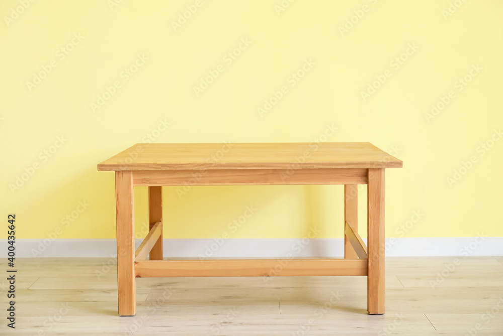 Stylish table near color wall in room