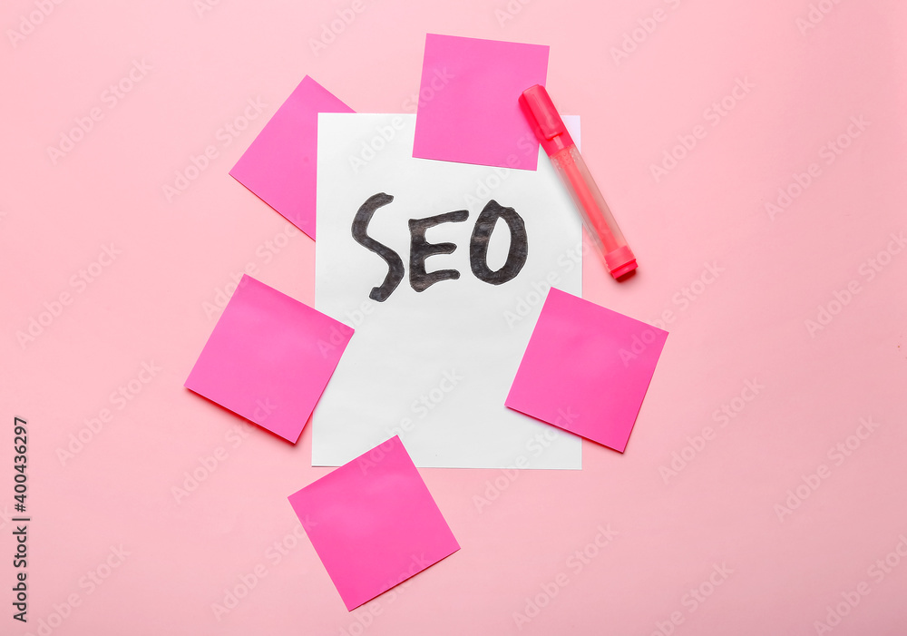 Paper sheet with abbreviation SEO and stationery on color background